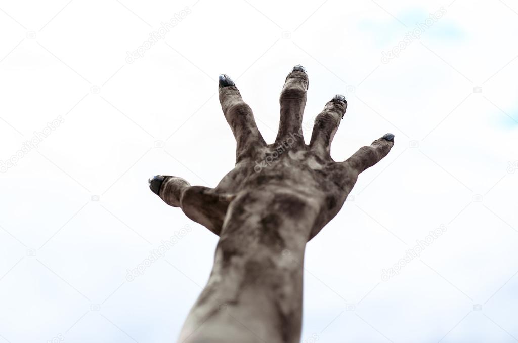 Horror and Halloween theme: Terrible zombie hands dirty with black nails reach for the sky, walking dead apocalypse, first-person view