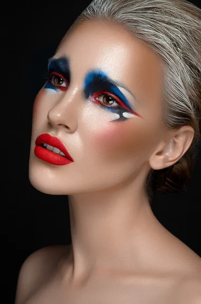 Tema del arte del maquillaje: hermosa chica con maquillaje azul y rojo y cabello blanco sobre un fondo aislado oscuro en el estudio — Foto de Stock