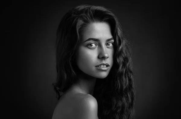 Dramatic portrait of a girl theme: Black and white portrait of a young beautiful girl on a dark background in the studio — Stock Photo, Image