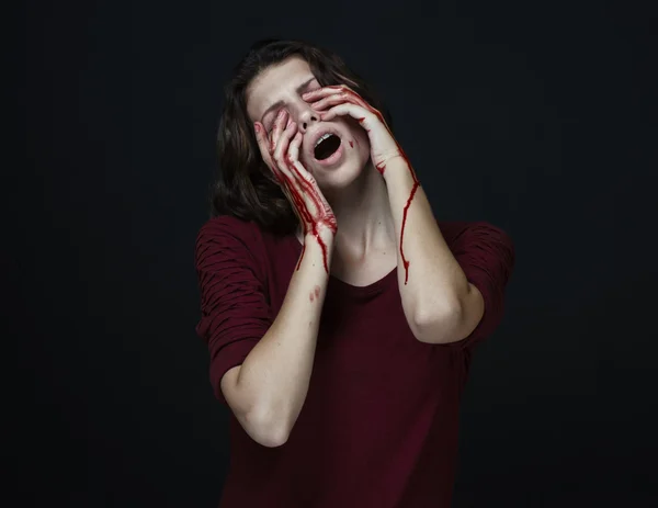 Gruseliges Mädchen und Halloween-Thema: Porträt eines verrückten Mädchens mit blutiger Hand bedeckt das Gesicht im Studio auf dunklem Hintergrund, blutige Tränen — Stockfoto