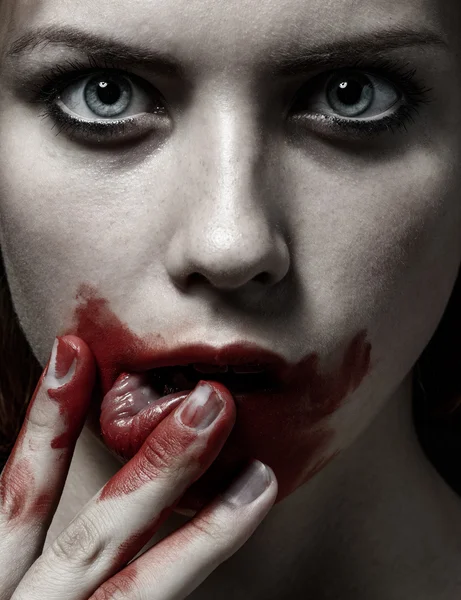 Scary Girl and Halloween theme: portrait of a crazy girl with a bloody face in the studio