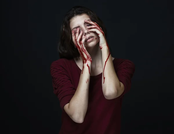 Gruseliges Mädchen und Halloween-Thema: Porträt eines verrückten Mädchens mit blutiger Hand bedeckt das Gesicht im Studio auf dunklem Hintergrund, blutige Tränen — Stockfoto