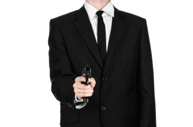Firearms and security topic: a man in a black suit holding a gun on an isolated white background in studio