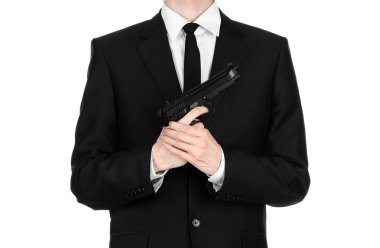 Firearms and security topic: a man in a black suit holding a gun on an isolated white background in studio