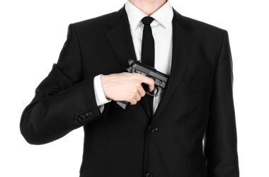 Firearms and security topic: a man in a black suit holding a gun on an isolated white background in studio