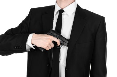 Firearms and security topic: a man in a black suit holding a gun on an isolated white background in studio