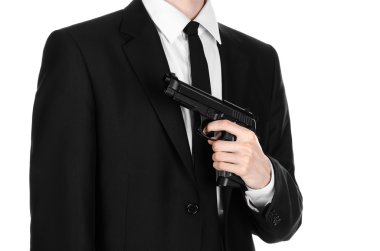 Firearms and security topic: a man in a black suit holding a gun on an isolated white background in studio