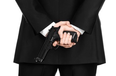 Firearms and security topic: a man in a black suit holding a gun on an isolated white background in studio