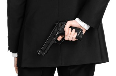 Firearms and security topic: a man in a black suit holding a gun on an isolated white background in studio