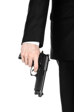 Firearms and security topic: a man in a black suit holding a gun on an isolated white background in studio