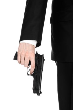 Firearms and security topic: a man in a black suit holding a gun on an isolated white background in studio