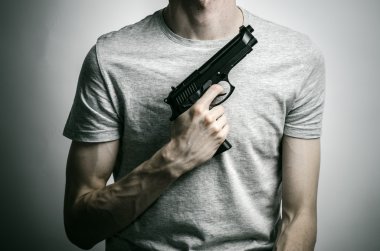 Horror and firearms topic: suicide with a gun on a gray background in the studio
