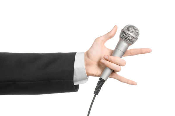 Business en spraak onderwerp: Man in zwart pak houden een grijze microfoon op een afgelegen witte achtergrond in studio — Stockfoto