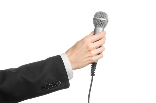 Üzleti és beszéd téma: férfi gazdaság egy szürke mikrofon, stúdió egy elszigetelt fehér alapon fekete öltöny — Stock Fotó
