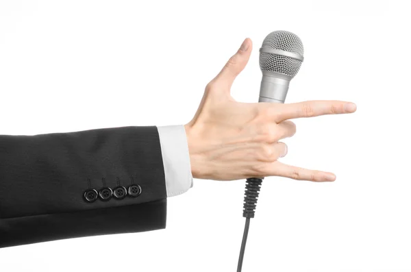Тема бізнесу та мови: Чоловік у чорному костюмі тримає сірий мікрофон на ізольованому білому тлі в студії — стокове фото