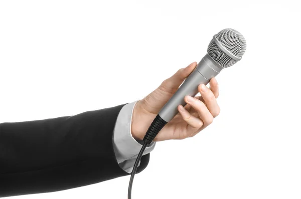 Tema de negocios y habla: Hombre de traje negro sosteniendo un micrófono gris sobre un fondo blanco aislado en el estudio — Foto de Stock