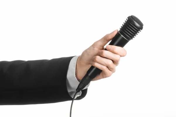 Тема бізнесу та мови: Чоловік у чорному костюмі тримає чорний мікрофон ізольовано на білому тлі в студії — стокове фото