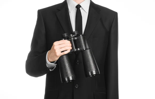 Tópico de negócios e pesquisa: Homem de terno preto segurando um binóculos pretos na mão sobre fundo isolado branco em estúdio — Fotografia de Stock