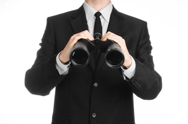 Business and search topic: Man in black suit holding a black binoculars in hand on white isolated background in studio — 스톡 사진