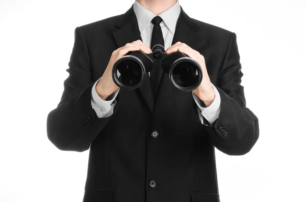 Tópico de negócios e pesquisa: Homem de terno preto segurando um binóculos pretos na mão sobre fundo isolado branco em estúdio — Fotografia de Stock