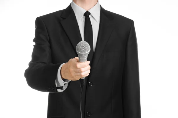 业务和演讲主题: 握着灰色的麦克风在工作室中孤立白色背景上的黑色西装的男人 — 图库照片