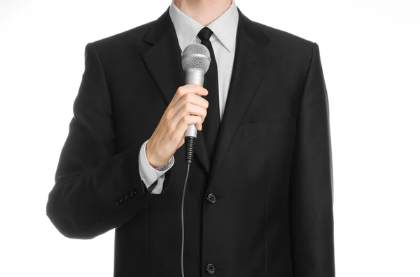 业务和演讲主题: 握着灰色的麦克风在工作室中孤立白色背景上的黑色西装的男人 — 图库照片
