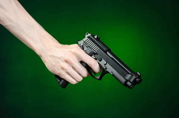 Огнестрельное оружие и тема убийцы: человеческая рука, держащая пистолет на темно-зеленом фоне, изолированная в студии — стоковое фото