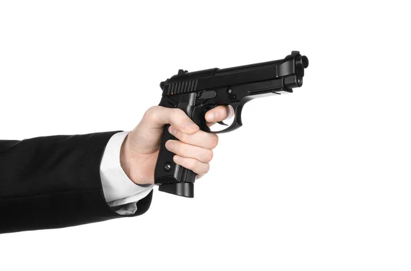 Armas de fogo e tópico de segurança: um homem de terno preto segurando uma arma em um fundo branco isolado no estúdio — Fotografia de Stock
