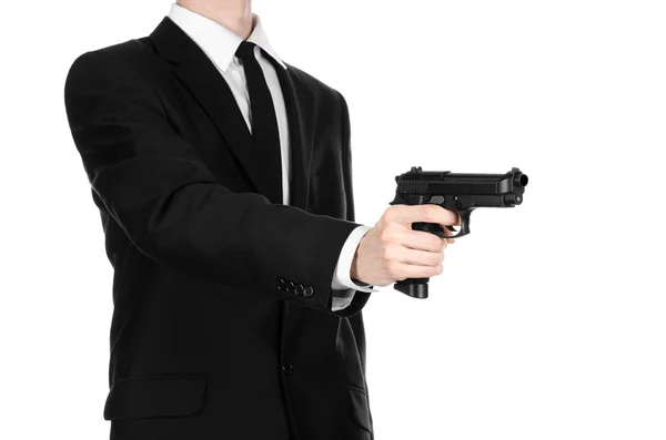 Firearms and security topic: a man in a black suit holding a gun on an isolated white background in studio — Zdjęcie stockowe