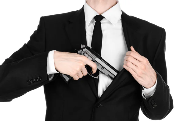 Тема огнестрельного оружия и безопасности: человек в черном костюме, держащий пистолет на изолированном белом фоне в студии — стоковое фото