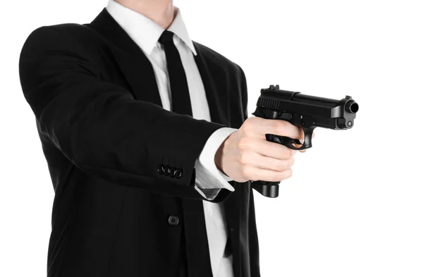 Armas de fogo e tópico de segurança: um homem de terno preto segurando uma arma em um fundo branco isolado no estúdio — Fotografia de Stock