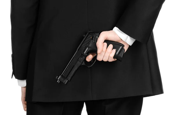 Зброя та тема безпеки: чоловік у чорному костюмі тримає пістолет на ізольованому білому тлі в студії — стокове фото