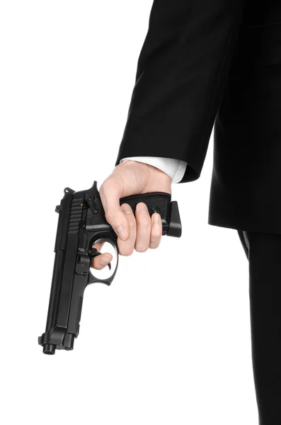 Armas de fuego y temas de seguridad: un hombre con un traje negro sosteniendo un arma sobre un fondo blanco aislado en el estudio —  Fotos de Stock
