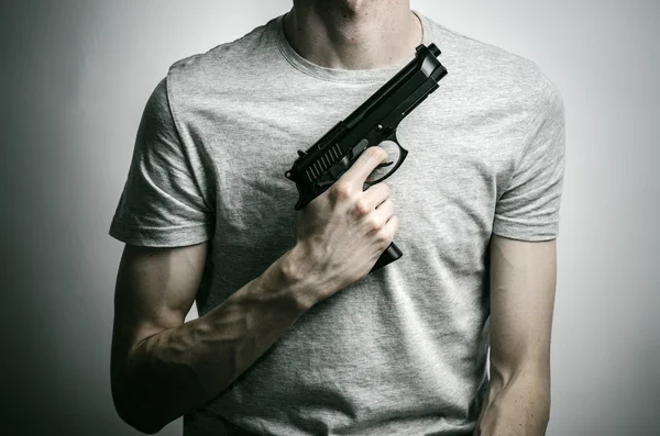 Tópico de terror e armas de fogo: suicídio com uma arma em fundo cinza no estúdio — Fotografia de Stock