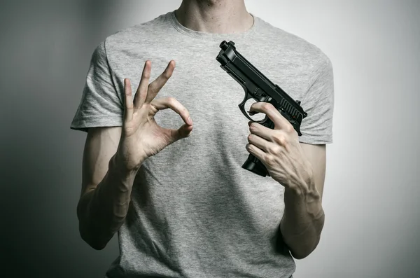 Horror and firearms topic: suicide with a gun on a gray background in the studio — Stock Fotó