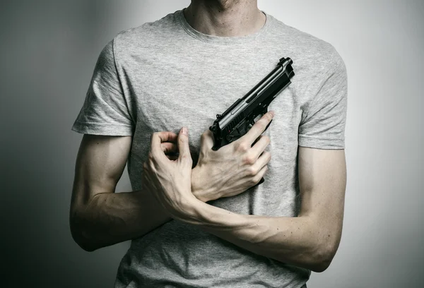Horror and firearms topic: suicide with a gun on a gray background in the studio — 스톡 사진