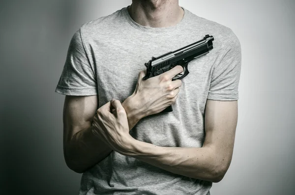 Tópico de terror e armas de fogo: suicídio com uma arma em fundo cinza no estúdio — Fotografia de Stock