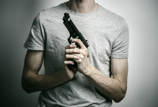 Horror and firearms topic: suicide with a gun on a gray background in the studio — 스톡 사진