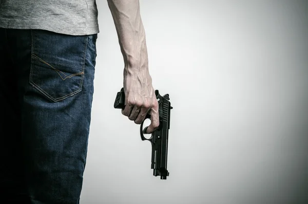 Horror and firearms topic: crazed killer with a gun on a gray background in the studio — 스톡 사진