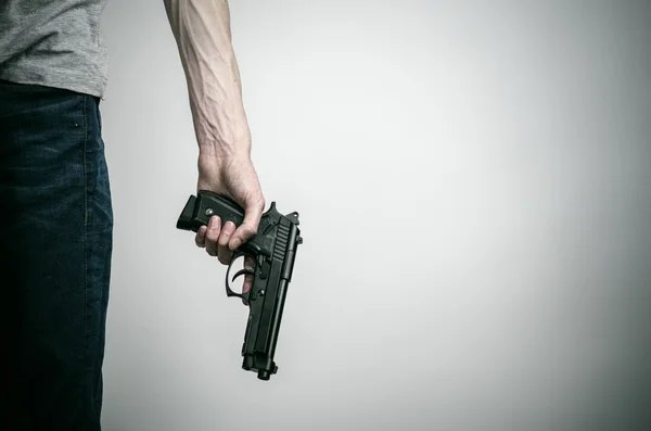 Horror and firearms topic: suicide with a gun on a gray background in the studio — 스톡 사진