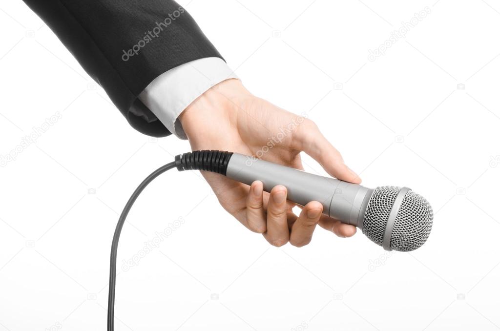 Business and speech topic: Man in black suit holding a gray microphone on an isolated white background in studio