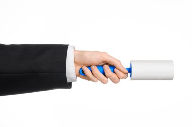 Dry cleaning and business theme: a man in a black suit holding a blue sticky brush for cleaning clothes and furniture from dust isolated on white background in studio.