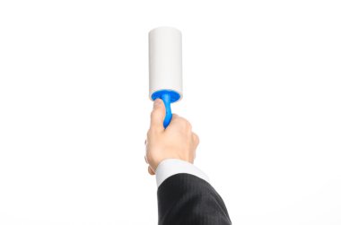 Dry cleaning and business theme: a man in a black suit holding a blue sticky brush for cleaning clothes and furniture from dust isolated on white background in studio.