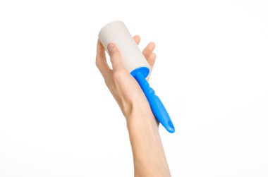 Clean clothes and cleaning the house topic: human hand holding a blue sticky brush for cleaning clothes and furniture from dust isolated on white background in studio.