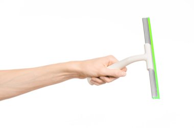 Household cleaning and washing windows theme: man's hand holding a green scraper windows isolated on a white background in the studio.