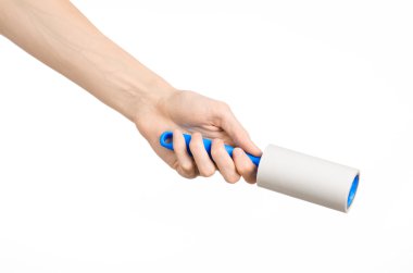 Clean clothes and cleaning the house topic: human hand holding a blue sticky brush for cleaning clothes and furniture from dust isolated on white background in studio.