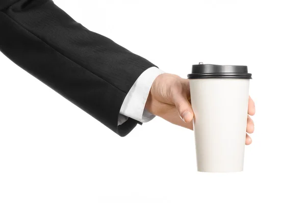 Business lunches coffee theme: businessman in a black suit holding a white blank paper cup of coffee with a brown plastic cap isolated on a white background in the studio, advertising coffee — Stockfoto