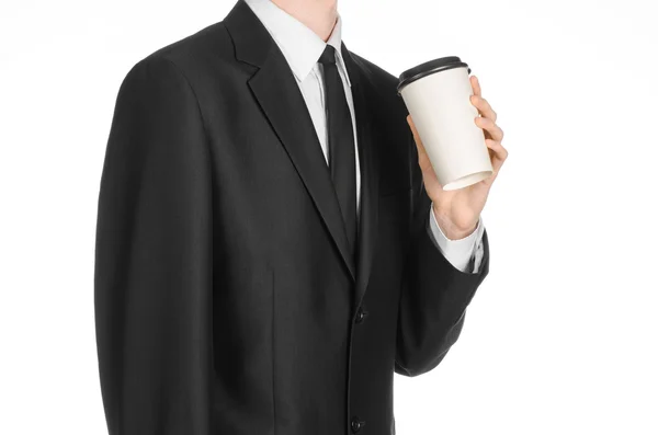 Almuerzos de negocios tema de café: hombre de negocios en un traje negro sosteniendo una taza de papel blanco de café con una tapa de plástico marrón aislado sobre un fondo blanco en el estudio, publicidad de café — Foto de Stock