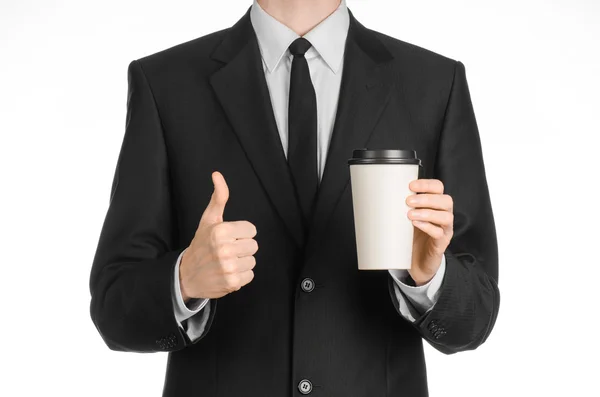 Almoços de negócios tema do café: homem de negócios em um terno preto segurando uma xícara de café de papel branco em branco com uma tampa de plástico marrom isolado em um fundo branco no estúdio, café publicitário — Fotografia de Stock