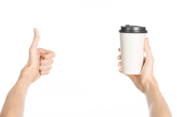 Breakfast and coffee theme: man's hand holding white empty paper coffee cup with a brown plastic cap isolated on a white background in the studio, advertising of coffee first-person view — Stock Photo, Image